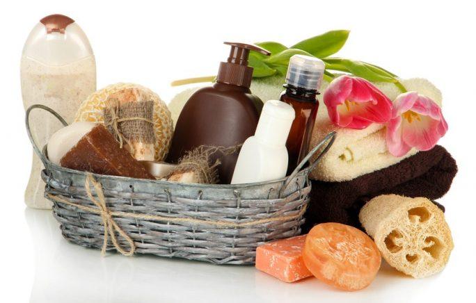Composition of cosmetic bottles and soap in basket, isolated on white